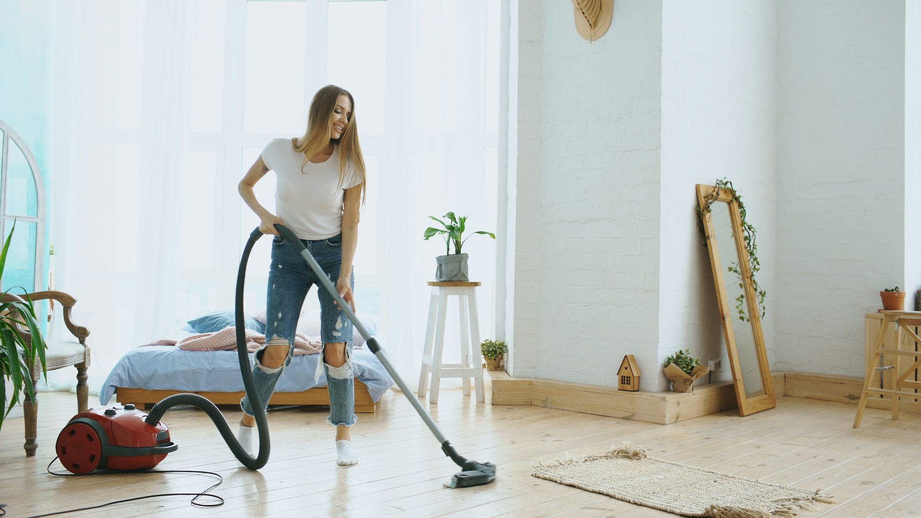 Illustrative photo of a person vacuuming a bright living room